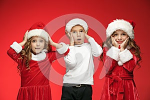 The happy boy and girls in santa claus hats with gift boxes at studio