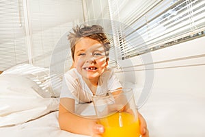 Happy boy with glass of juice in sunny morning