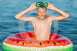 Happy boy in glasses for swimming on an inflatable circle swims in the sea. A little boy has fun and swims on an inflatable circle