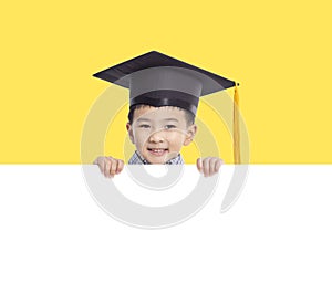 Happy boy in graduation cap holding white empty banner