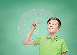 Happy boy in green polo t-shirt pointing finger up