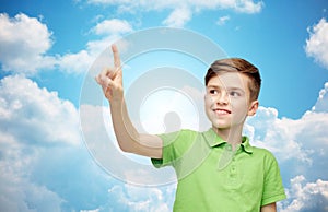 Happy boy in green polo t-shirt pointing finger up