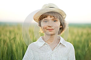 Happy boy in the hat among the wheat field