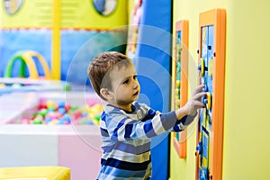 Happy boy having fun in ball pit in kids amusement park and indoor play center. Child playing with colorful balls in playground