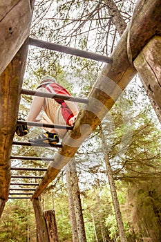 Happy boy having fun climbing on ladder in the forest