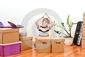 Happy boy having fun during moving day to a new house. Housing for young family with children. Child making roof hands