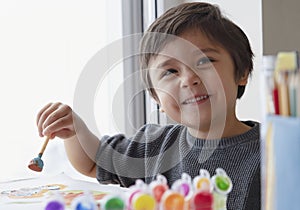 Happy boy having fun painting water colour on paper,Kid holding art brush learning painting and drawing at home,Indoor activities