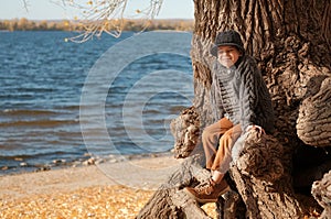 Happy boy having fun sitting on the tree at the beach