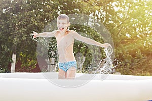 Happy boy having fun in the swimming pool with father in the garden at summer