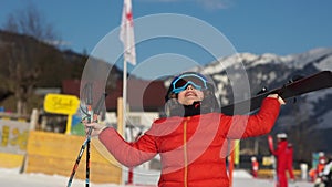Happy boy in helmet and ski goggles with sticks and skis in the hands of a ski resort. Rejoicing, child fooling around