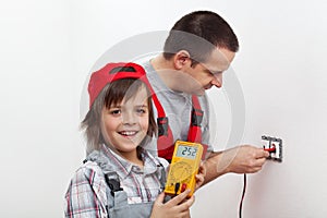 Happy boy helping his father mounting electrical wall fixtures