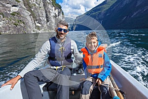 Happy boy with his father driving the motorboat, Norway. They are enjoying the moment.