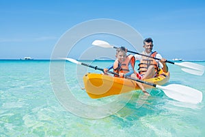 Happy boy and his father kayaking at tropical sea on yellow kayak