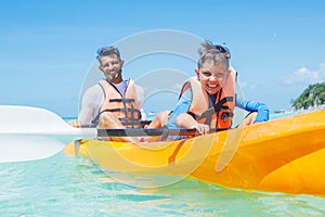 Happy boy and his father kayaking at tropical sea on yellow kayak