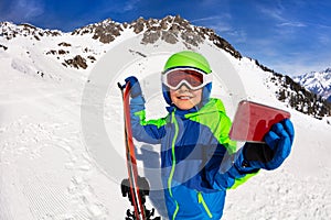 Happy boy hold ski taking picture with cell phone