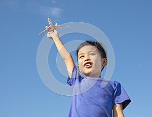 Happy boy holding a airplane toy with blue sky