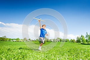 Happy boy holding airplane toy during running