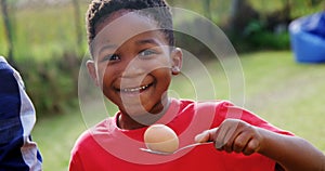 Happy boy holding egg and spoon in backyard 4k