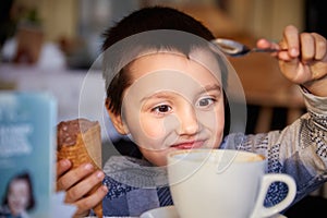 Happy boy holding ice cream cone and playing with tea spoon