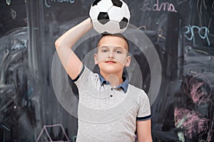 Happy boy holding a soccer ball on his head