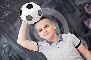 Happy boy holding a soccer ball on his head