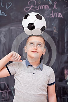 Happy boy holding a soccer ball on his head