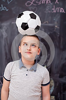 Happy boy holding a soccer ball on his head