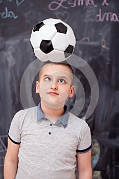Happy boy holding a soccer ball on his head