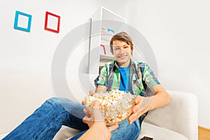 Happy boy holds popcorn bowl from someone's hand