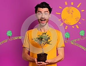 Happy boy holds a small tree ready to be planted over a light color. concept of forestation, ecology and conservation