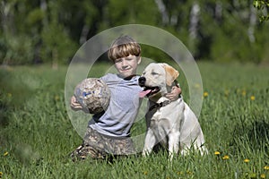 Happy boy hugging his dog breed Labrador. Best friends rest and have fun on vacation, play with soccer ball