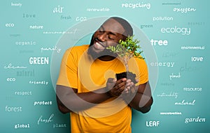 Happy boy hugs a small tree ready to be planted over a light blue color. Concept of forestation, ecology and