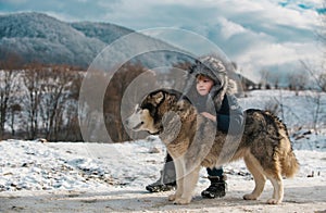 Happy boy with husky dog having fun on winter day outdoors.