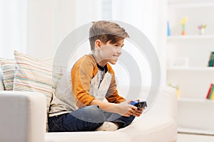 Happy boy with joystick playing video game at home