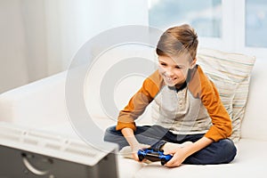 Happy boy with joystick playing video game at home