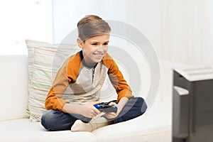 Happy boy with joystick playing video game at home