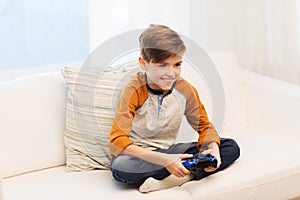 Happy boy with joystick playing video game at home