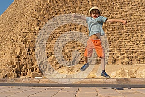 Happy boy jumping in front of the Cheops pyramid on the Giza plateau