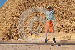 Happy boy jumping in front of the Cheops pyramid on the Giza plateau