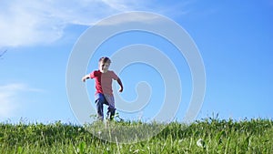 Happy boy jumping on green grass hill