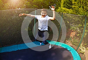Happy boy jumping high on the backyard trampoline