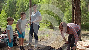 Happy boy jumping joyfully. Two women and two boys having summer camping vacation in forest. Family of two mothers and