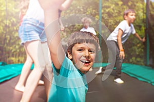 Happy boy jumping on trampoline with his friends