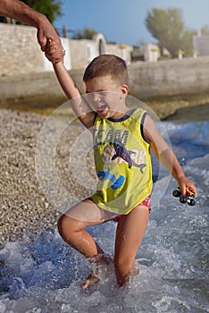 Happy boy jumping in the water on the beach playing playing with the waves in the sea and having fun