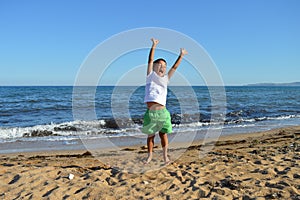 Happy boy jumps on the beach by the sea