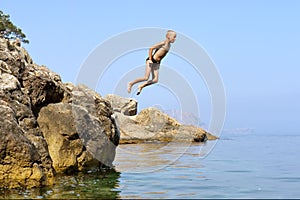 Contento ragazzo salta la roccia il mare 