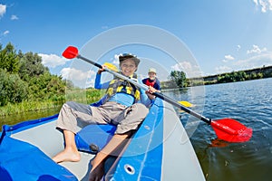 Happy boy kayaking on the river on a sunny day during summer vacation