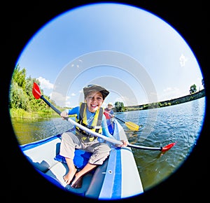 Happy boy kayaking on the river on a sunny day during summer vacation