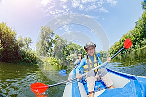 Happy boy kayaking on the river on a sunny day during summer vacation