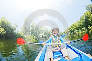 Happy boy kayaking on the river on a sunny day during summer vacation